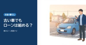 夕方の中古車の駐車場で、年式の古いコンパクトカーの横に立ちスマホを見ながら考える男性